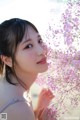 A woman holding a bunch of pink flowers in her hand.