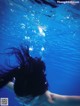 A woman swimming underwater with her hair blowing in the wind.